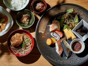 una mesa con un plato de comida con fideos y otros alimentos en Daiwa Roynet Hotel Toyama-Ekimae en Toyama