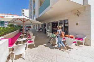 a woman walking past a restaurant with tables and chairs at Dubrovnik Luxury Residence – L’Orangerie in Dubrovnik