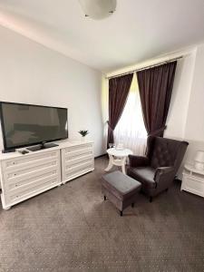 a living room with a large television and a chair at Hotel Park in Opoczno