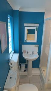 a blue bathroom with a sink and a toilet at Poplars in Aldeburgh