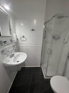 a white bathroom with a shower and a sink at Hotel Park in Opoczno