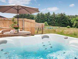 a hot tub with an umbrella in a yard at Cosy cottage in the Blackdown hills Devon in Honiton