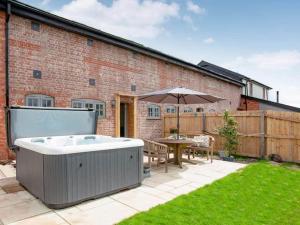 a backyard with a hot tub and a table and an umbrella at Cosy cottage in the Blackdown hills Devon in Honiton