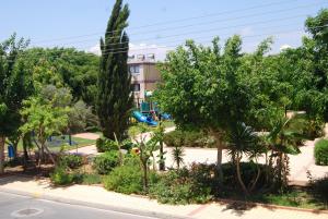 un parque con árboles y un parque infantil con tobogán. en Agrino Hotel Apartments, en Ayia Napa