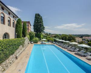 a swimming pool with chairs and umbrellas next to a building at Residence La Filanda in Costermano