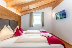 a bedroom with a large bed with red pillows at Appartements Ferienwohnungen Unser Unterberg in Maria Alm am Steinernen Meer