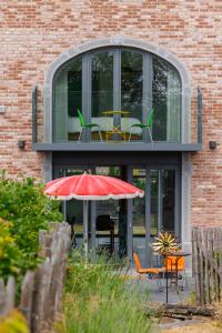 a building with tables and chairs and an umbrella at Cerf, ouvre-moi B&B in Rochefort