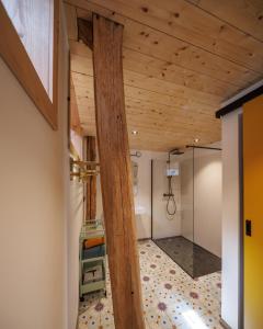 een kamer met een houten plafond en een glazen douche bij Cerf, ouvre-moi B&B in Rochefort