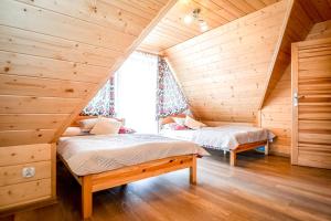 2 camas en un ático con paredes de madera en Willa Góralska en Biały Dunajec