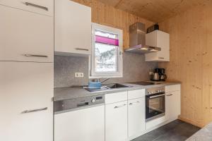 a white kitchen with white cabinets and a window at Feriendorf Murau by ALPS RESORTS in Murau