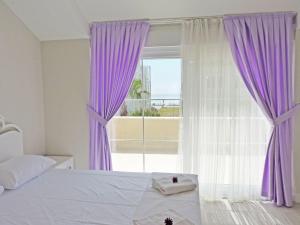 a bedroom with purple curtains and a large window at Roma Residence - Emir Gürsu Evleri in Antalya