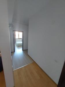 Una habitación vacía con una pared blanca y pisos de madera. en Roxana apartament 3 camere, en Râmnicu Vâlcea 2 fotos más