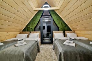 two beds in a room with wooden ceilings at Kompleks Gazdówka Domki Rabka-Zdrój in Ponice