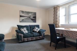 a living room with a couch and a table at Modern 2 bed flat, private parking & sec entry in Gourock