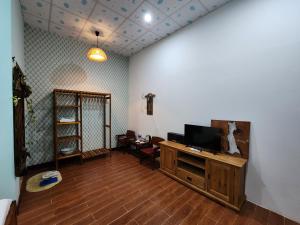 sala de estar con TV de pantalla plana en un centro de entretenimiento de madera en Tầm Quên Homestay, en Tây Ninh