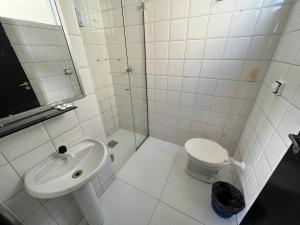 a white bathroom with a toilet and a sink at Hotel Viena in Taguatinga