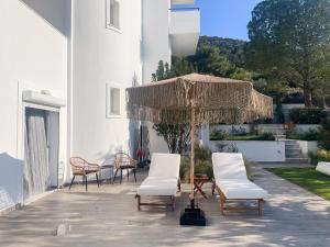 a group of chairs and an umbrella on a patio at My Porto Villa in Porto Rafti