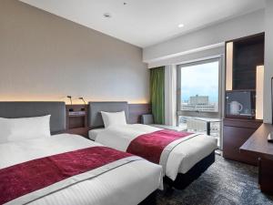 a hotel room with two beds and a window at Daiwa Roynet Hotel Toyama-Ekimae in Toyama