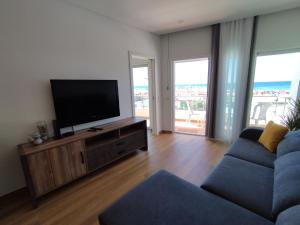 a living room with a tv and a blue couch at T2 - Praia Pescadores Frente Mar - Casas & Papéis in Armação de Pêra