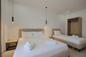 duas camas num quarto com lençóis brancos e toalhas em Hotel Edola em Saranda