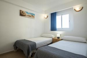 two beds in a room with a window at Apartamentos Torre Yago in Benidorm