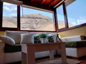 a living room with a couch and a table and windows at Finca Esperanza in Yaiza