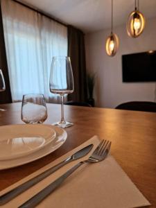 una mesa de madera con un plato y dos copas de vino en Onix - Nordic Studio Apartment 3, Premium Parking en Bucarest