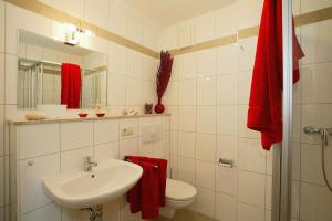 La salle de bains est pourvue d'un lavabo, de toilettes et de serviettes rouges. dans l'établissement Villa Sonnenstrand II, à Bansin