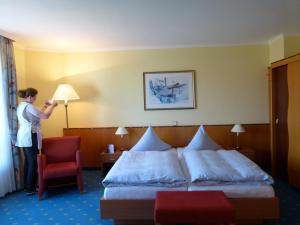 kobieta stojąca obok łóżka w pokoju hotelowym w obiekcie Aparthotel Kachelot w mieście Borkum