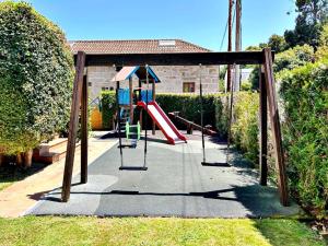 Un parque infantil con un tobogán en un patio en Holibai, Chuliña, Cerca de la playa, con piscina y parking, en Baiona