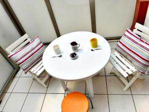une table blanche avec deux chaises et deux tasses dans l'établissement Holibai, Chuliña, En Urbanización privada con Piscina, à Baiona