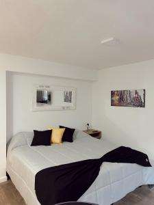 ein weißes Schlafzimmer mit einem großen Bett mit schwarzen und gelben Kissen in der Unterkunft Temporarios NYC - 1 (Córdoba) in Cordoba