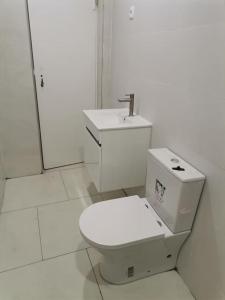 a white bathroom with a toilet and a sink at Homing Plateau - Apartment in the city of Praia in Praia