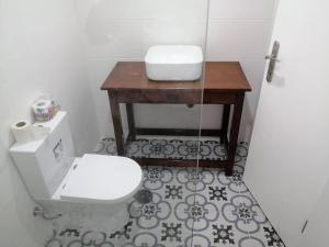 uma casa de banho com um WC e uma mesa de madeira em Homing Plateau - Apartment in the city of Praia em Praia