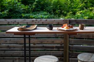 einem Holztisch mit Schuhen und einem Teller mit Essen in der Unterkunft Hutte Gartenland -KAIZUKA- ヒュッテ ガーテンラント カイヅカ in Karuizawa