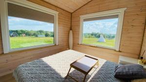 a bedroom with two windows and a bed and a chair at Lake House in Anykščiai