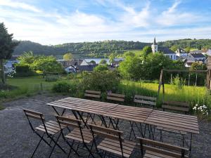 a wooden table and chairs with a view of a town at Haus mit idyllischem Seeblick in Schalkenmehren