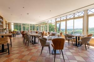 un restaurante con mesas, sillas y ventanas en Château de Sanse, en Sainte-Radegonde