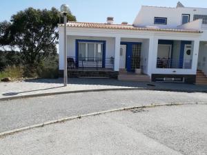 a white house with blue trim on a street at Brisamar in Aljezur