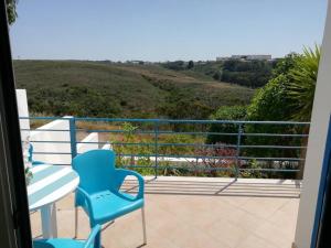 una silla azul sentada en un balcón con vistas en Brisamar, en Aljezur