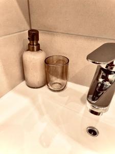 een wastafel in de badkamer met een zeepdispenser en een glas bij Villa Vilma in Sigulda
