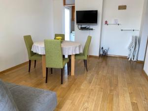 a dining room table with green chairs and a television at Apartment Franjo in Malinska