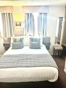 Schlafzimmer mit einem großen weißen Bett und blauen Vorhängen in der Unterkunft Clifton Court Hotel in Blackpool