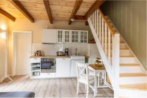 una cocina con armarios blancos, una mesa y una escalera en Ferienwohnungen Wildau am Werbellinsee, en Schorfheide