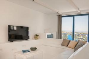 een woonkamer met een witte bank en een tv bij Villa Camelia-Iris sunset villas in Lépedha