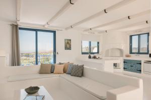 een witte woonkamer met een witte bank en ramen bij Villa Camelia-Iris sunset villas in Lépedha