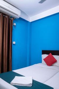 ein blaues Zimmer mit einem Bett und einem roten Kissen in der Unterkunft Shree Krishna GH in Guwahati
