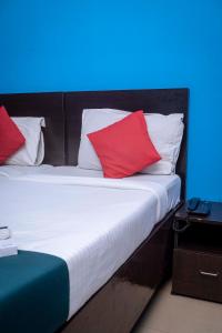 Una cama con almohadas rojas y blancas. en Shree Krishna GH en Guwahati