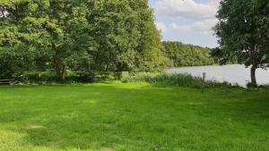 un campo de hierba con un lago en el fondo en Ferienhaus Am Schlenken Lychen Uckermark, en Lychen