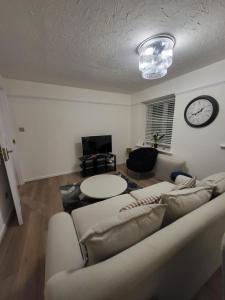 a living room with a couch and a clock on the wall at Lovely 2-Bed Apartment in Grays in South Ockendon